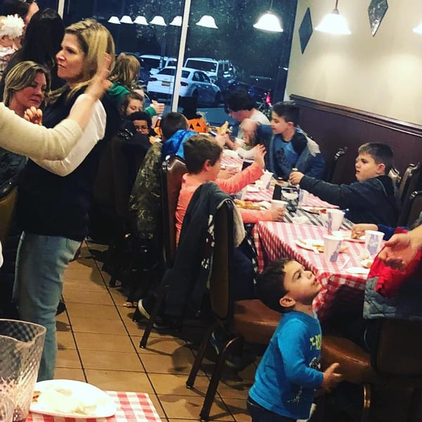 A lively Pennachio's pizza restaurant with families and children dining at checkered tables.
