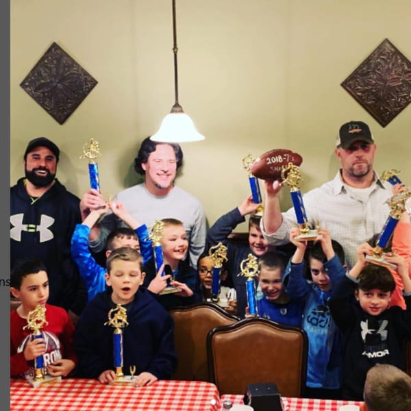 Adults and children celebrating with trophies at Pennachio's, a pizza restaurant.