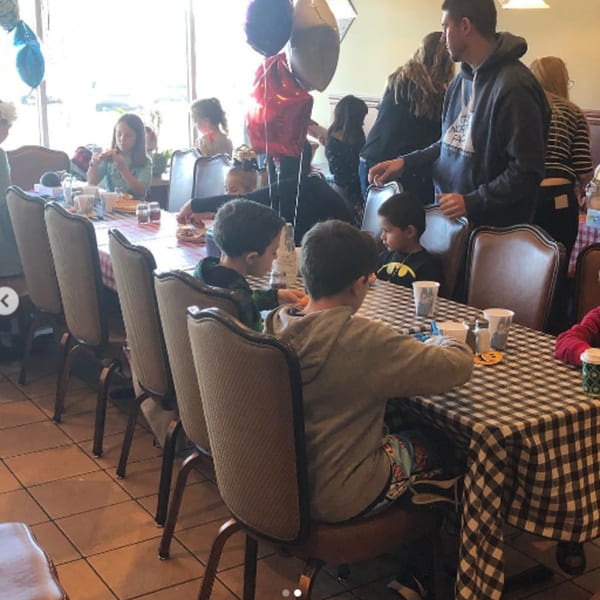 Children and adults gather around tables with checkered tablecloths, enjoying a meal at Pennachio's.