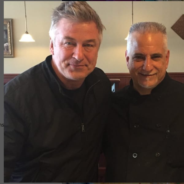 Alec Baldwin and a Pennachio's chef smiling together in the restaurant dining room.